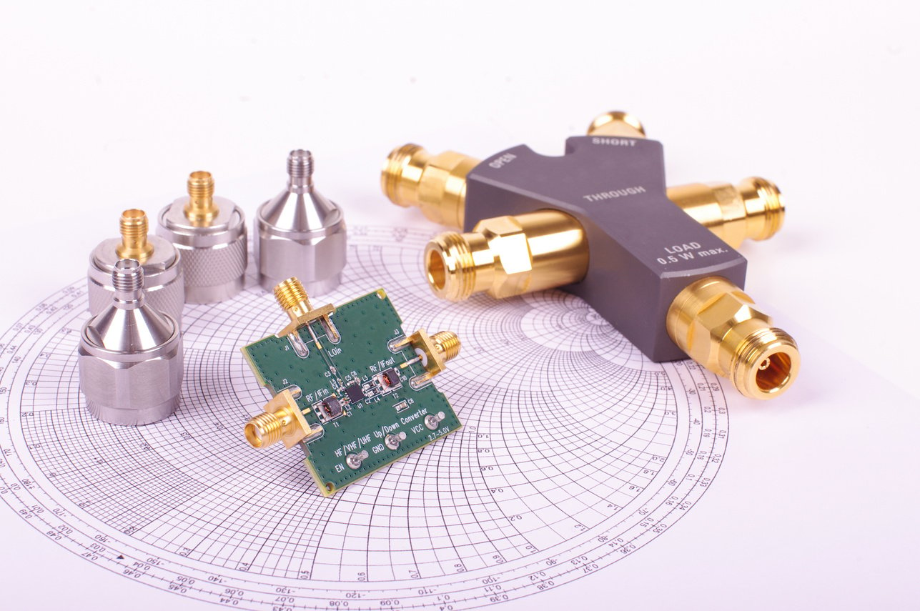 RF mixer electronics PCB in front of Smith chart and other microwave measurement tools and symbols